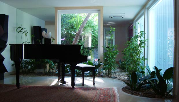 Este jardim começa na varanda e segue para dentro da sala de música, onde fica o piano da família. O ambiente ficou mais colorido com as plantas e ainda ganhou amplitude com as paredes espelhadas atrás do jardim. As espécies foram cultivadas próximo às pa<br>