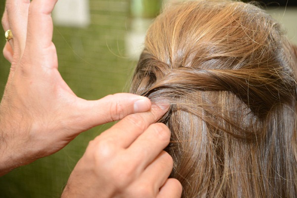 Juntar as duas mechas torcidas e prender com um grampo de baixo para cima.<br>