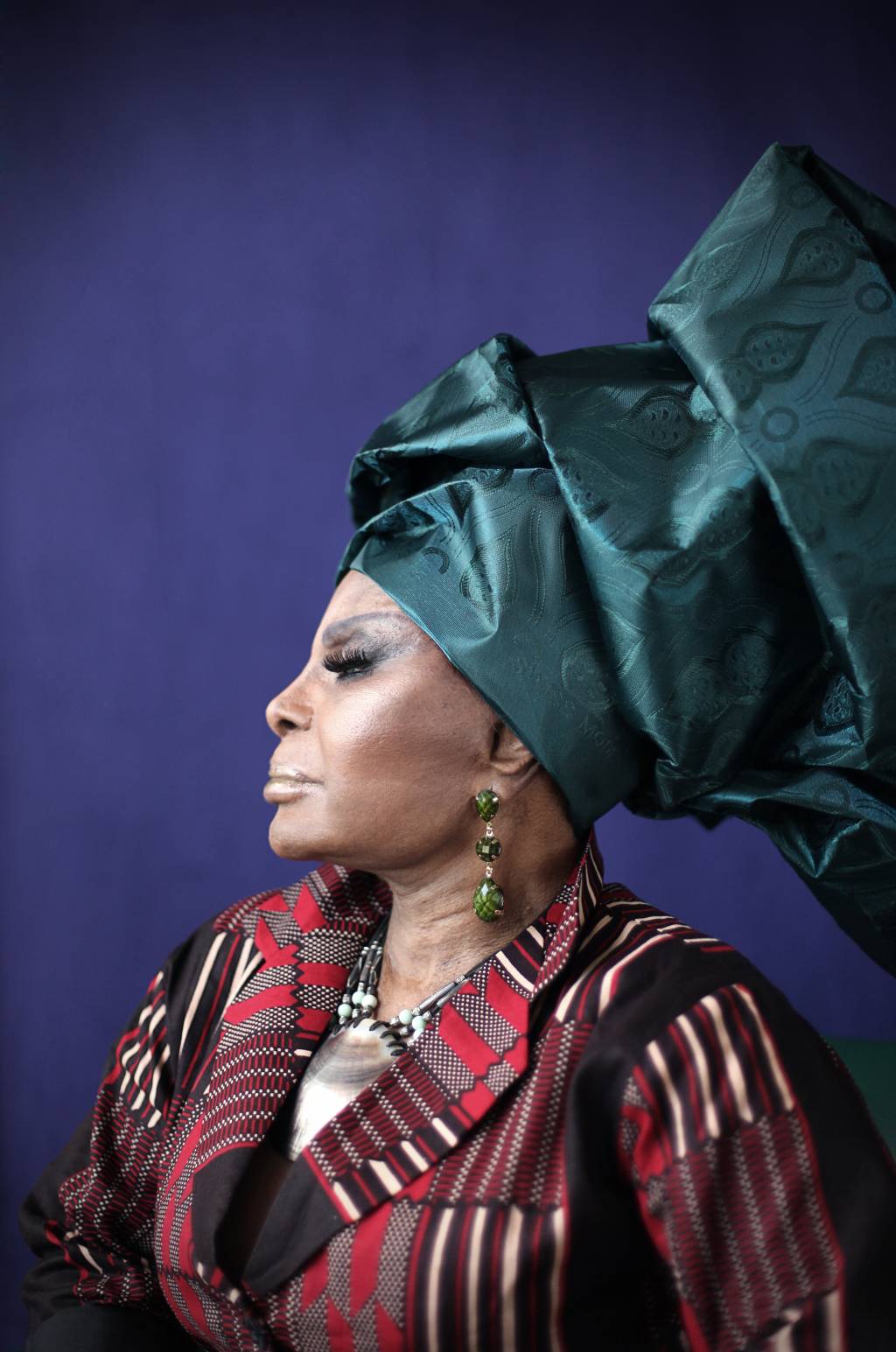 A imagem mostra Elza Soares, de perfil, usando um turbante