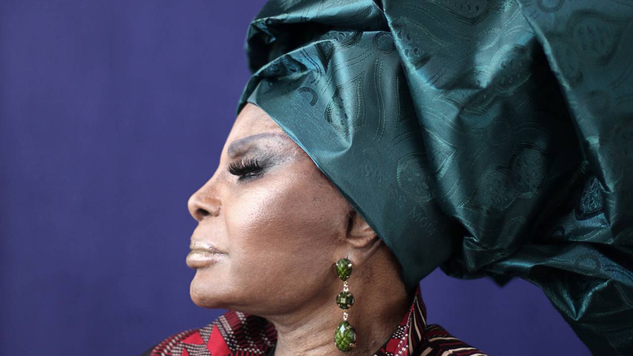 A imagem mostra Elza Soares, de perfil, usando um turbante