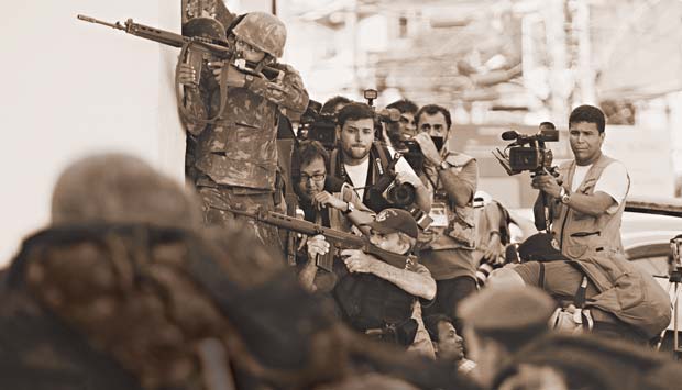 Jornalistas se protegem atrás dos policiais em meio ao confronto com traficantes na ocupação do Complexo do Alemão, em novembro do ano passado. O embate, que deixou 46 mortos, transformou o conjunto de treze favelas na Zona Norte da cidade em um cenário q