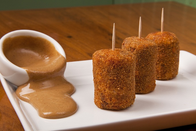 Mini croquetes de carne recheados com queijo e servidos com molho de mostarda são boa opção de entrada disponível no menu promocional<br>