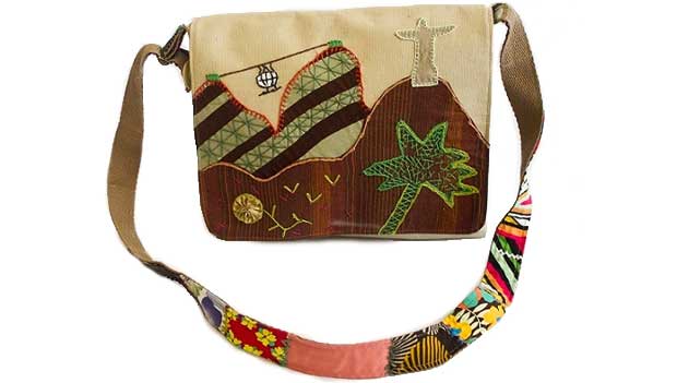 Bolsa carteiro da Oficina Toque de Mão (R$ 85,00), feita com restos de tecido, lona e banner publicitário. Os bordados são feitos à mão<br>