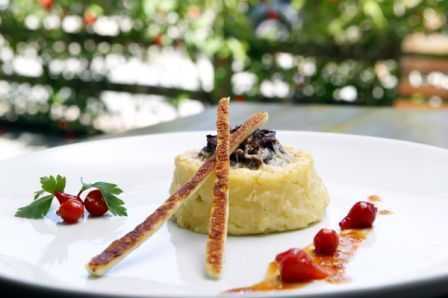 Petit gateau de semolina recheado com creme de porccini e carne seca: servido com telha de coalho, redução de pimenta porquinho e melaço de cana.<br>