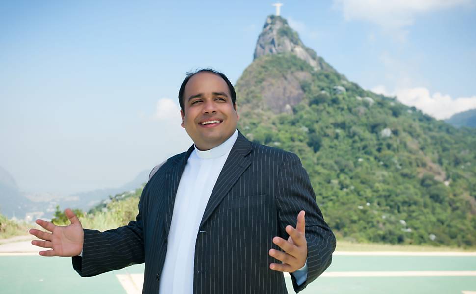 Padre Omar, de terno preto, posa na frente do Cristo Redentor