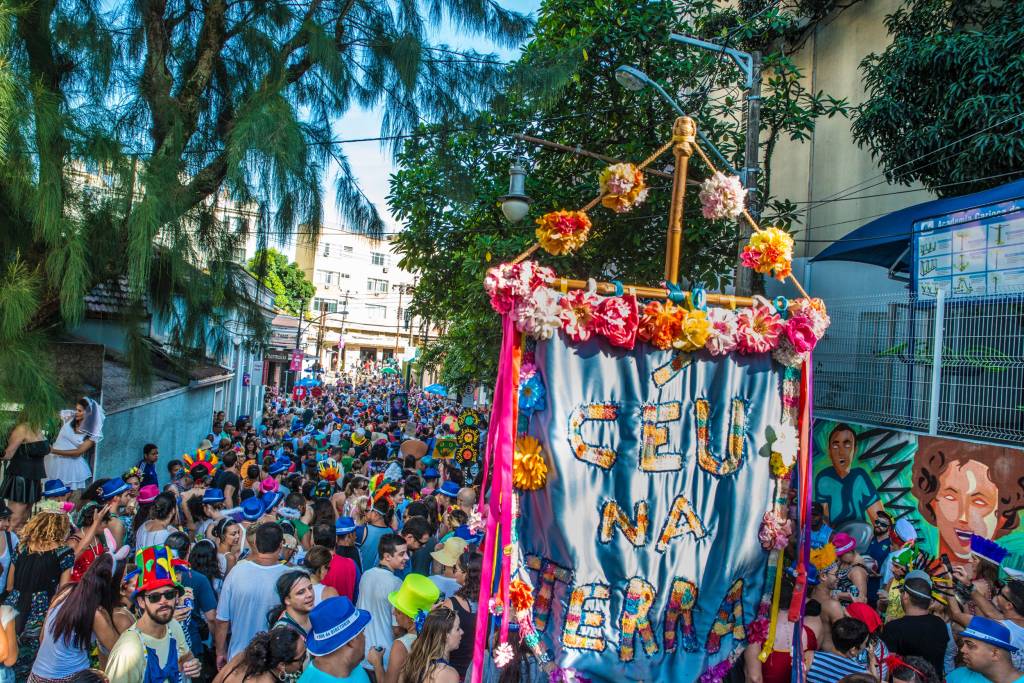 Bloco Céu na Terra desfilando por Santa Teresa com um grande estandarte na frente