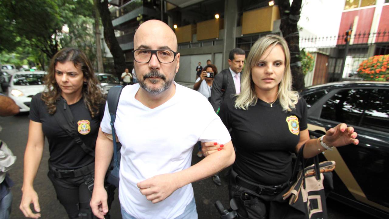 A imagem mostra o presidente da Fecomercio, Orlando DIniz, escoltado por duas policiais federais, ao ser preso