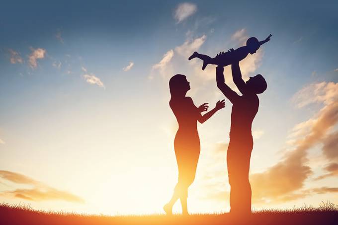 Happy family together, parents with their little child at sunset.
