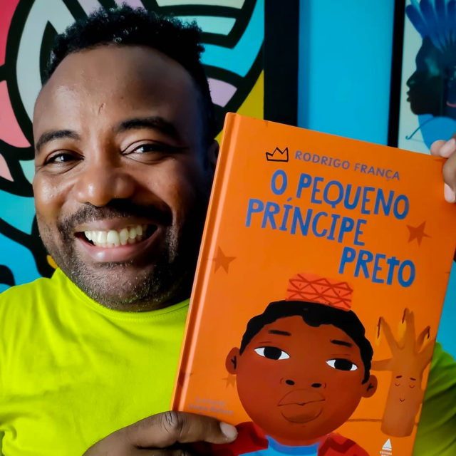 Rodrigo França segura o livro O Pequeno Principe Preto e sorri