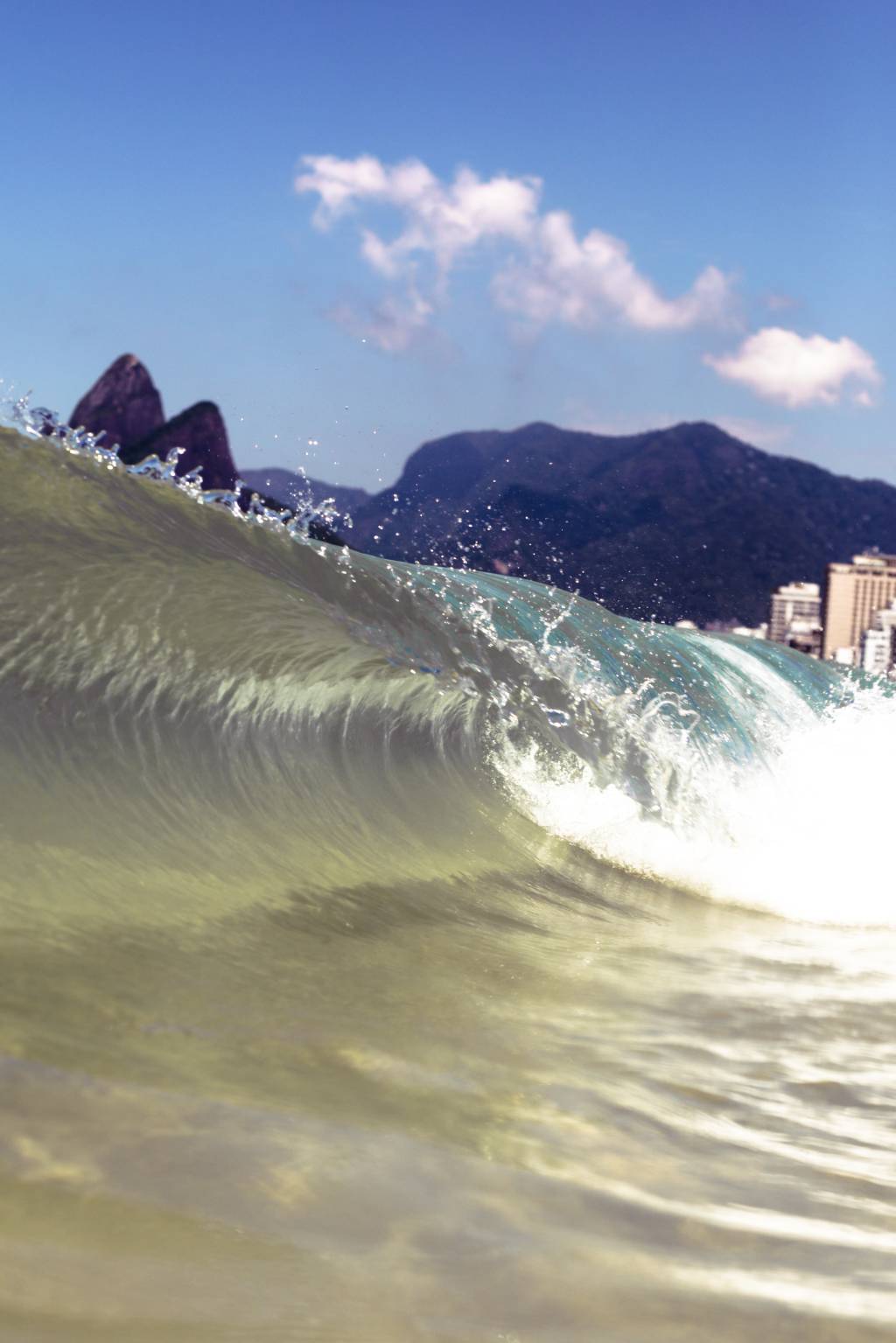 A imagem mostra uma onda quebrando na Praia de Ipanema