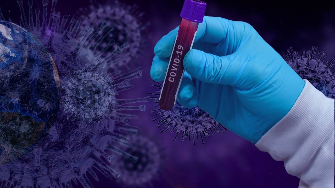 Imagem mostra amostra de sangue em frente à imagem que representa o vírus SARS-CoV-2