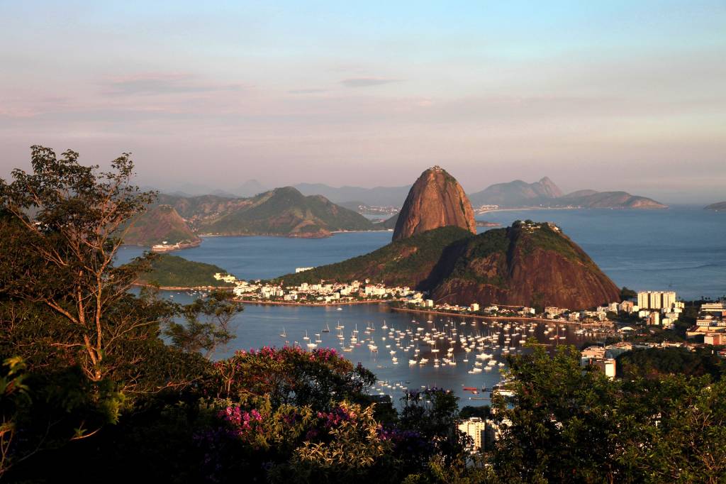 A imagem mostra o Rio de Janeiro do alto, com o Morro da Urca e o Pão de Açúcar, além da Baía de Guanabara