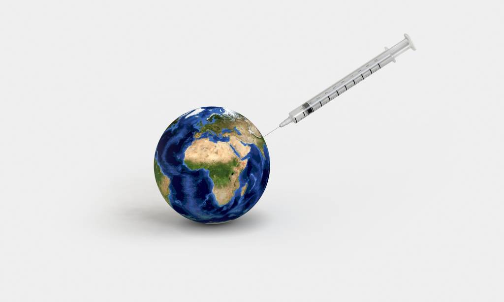 A imagem mostra uma seringa com vacina e globo terrestre