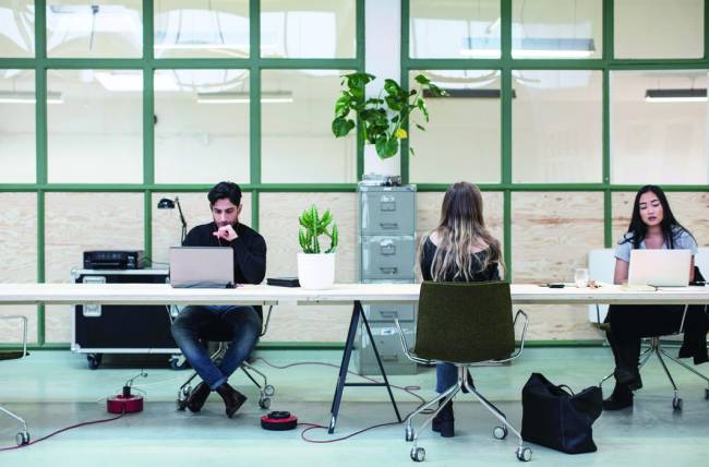 Two women and one man working at desk in creative office Two women and one man working at desk in creative office