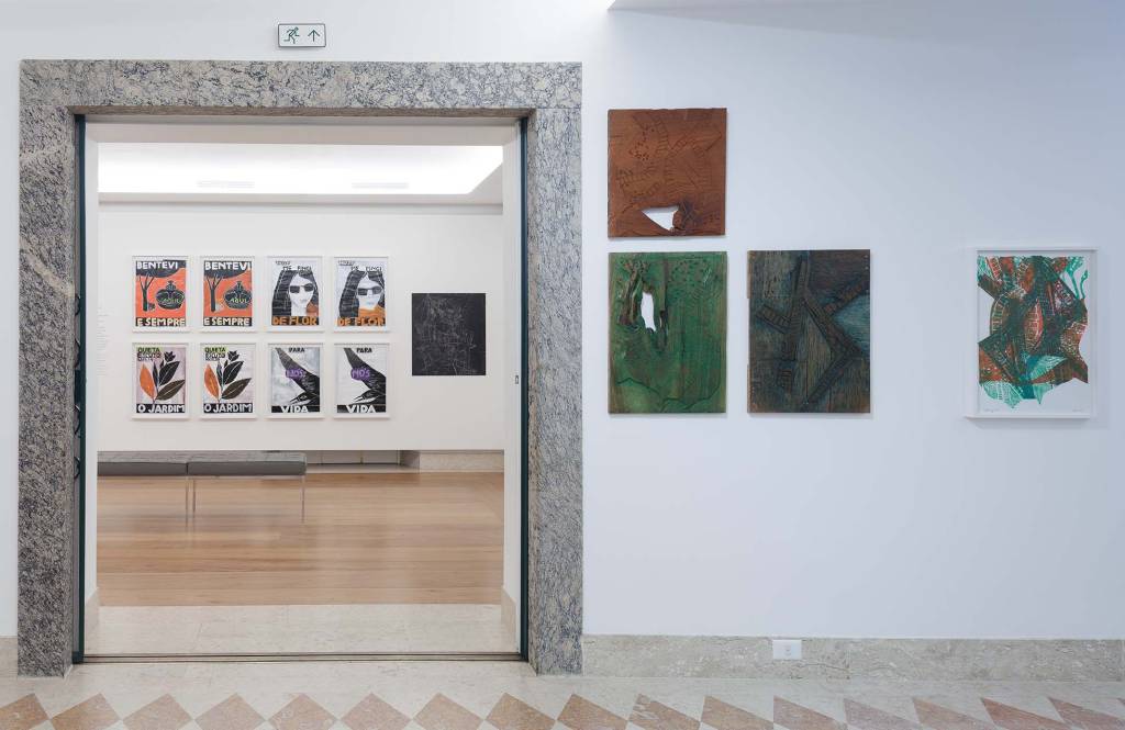 Parede da Casa Roberto Marinho com três quadros. Ao fundo, sala de exposição com diversos quadros presos à parede
