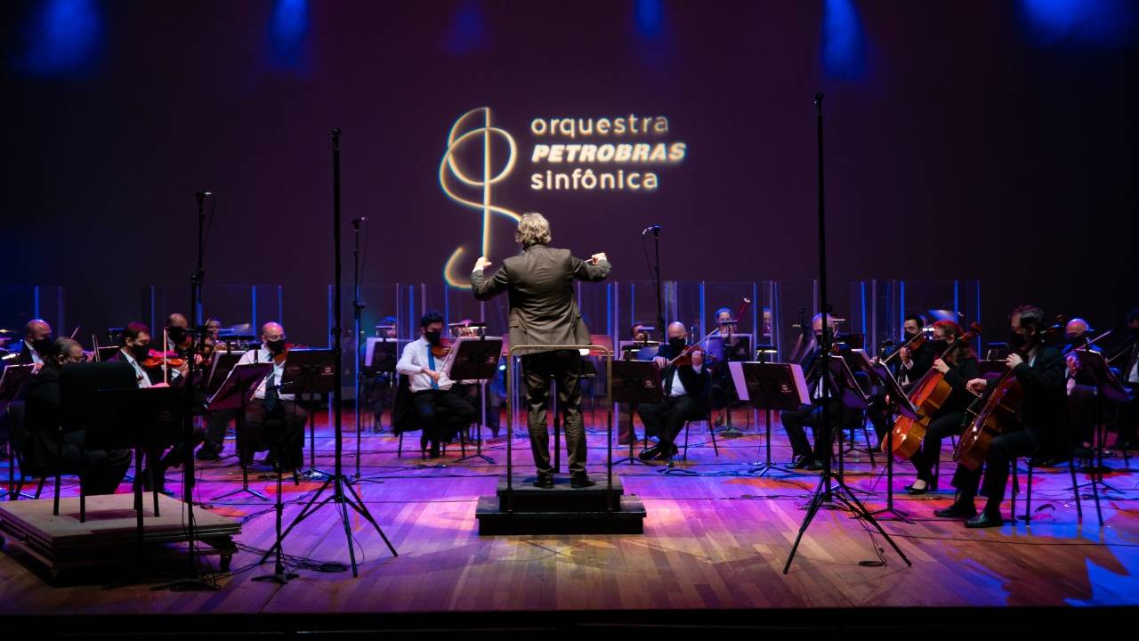 Orquestra Petrobras Sinfônica no palco, com o maestro de costas