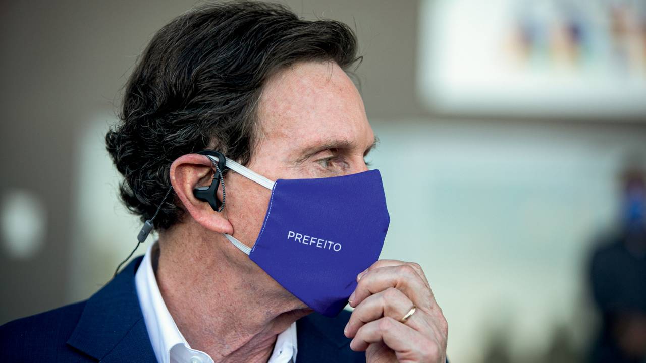 A imagem mostra o prefeito do Rio, Marcelo Crivella, de perfil, usando máscara de proteção azul