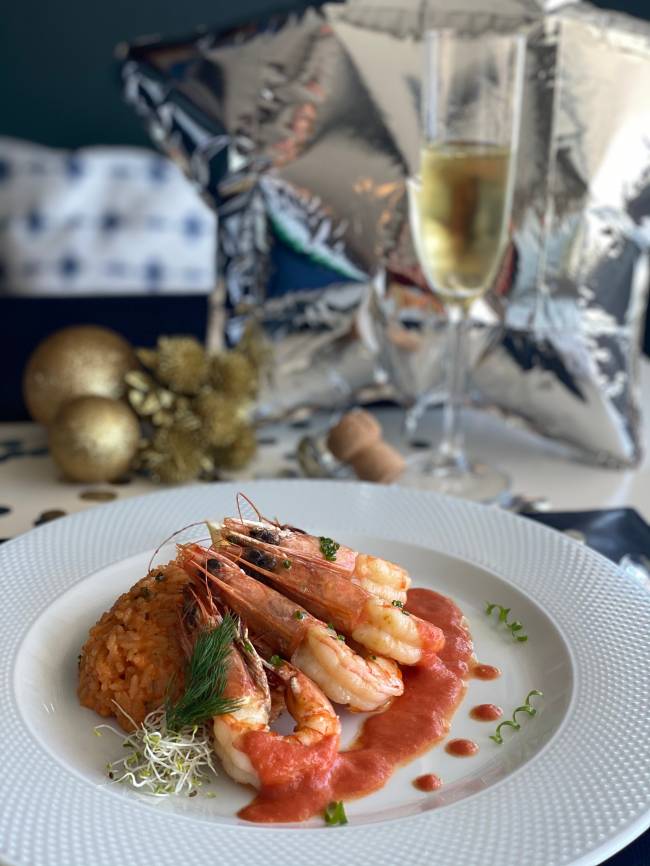 A imagem mostra um prato com camarão e lagosta