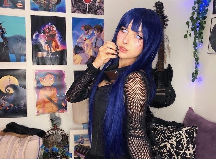 Jovem adolescente com cabelos coloridos de azul num quarto com guitarra e poster