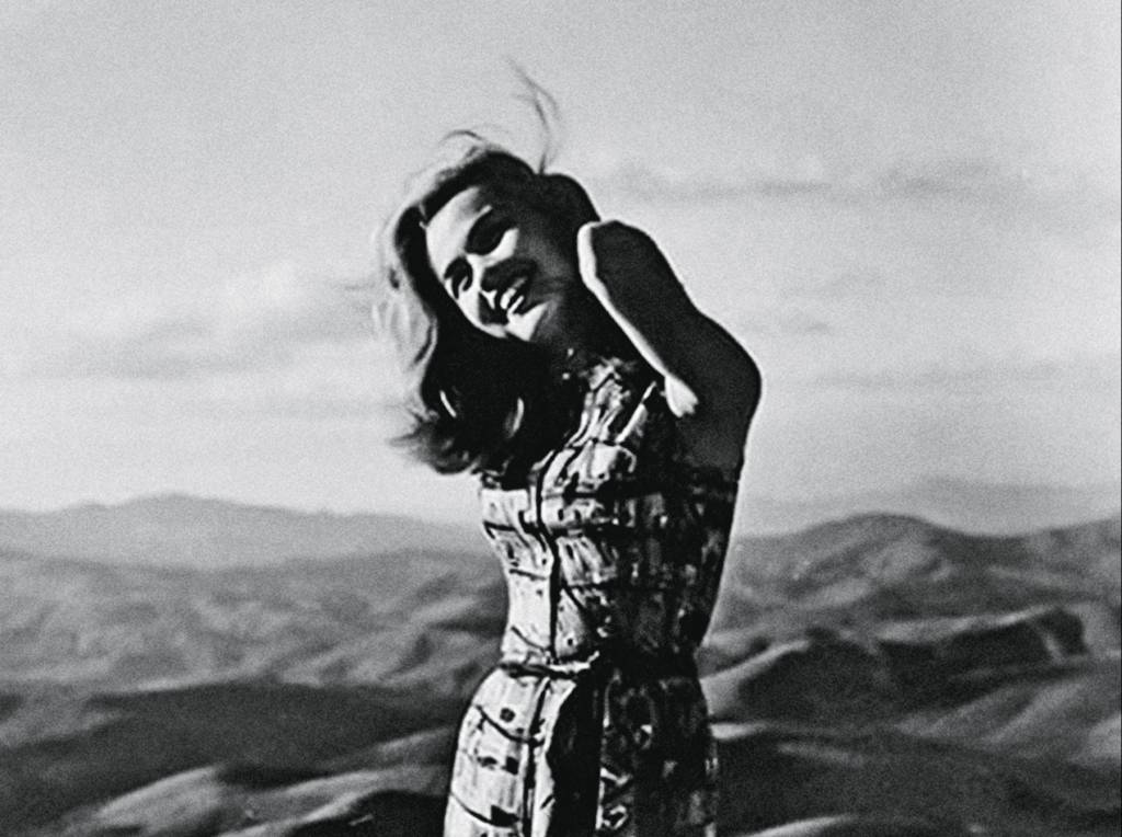 Angela Diniz com um dos cotovelos colado ao rosto, num cenário montanhoso. A foto é preto e branco