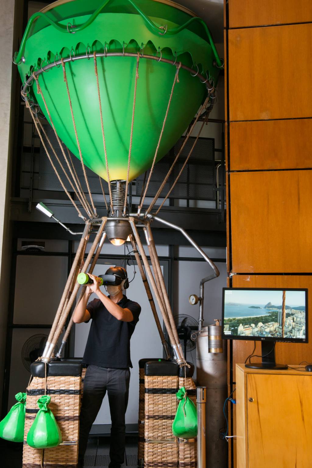 Homem munido de fones de ouvido e óculos de realidade virtual em balão cenográfico no Oi Futuro