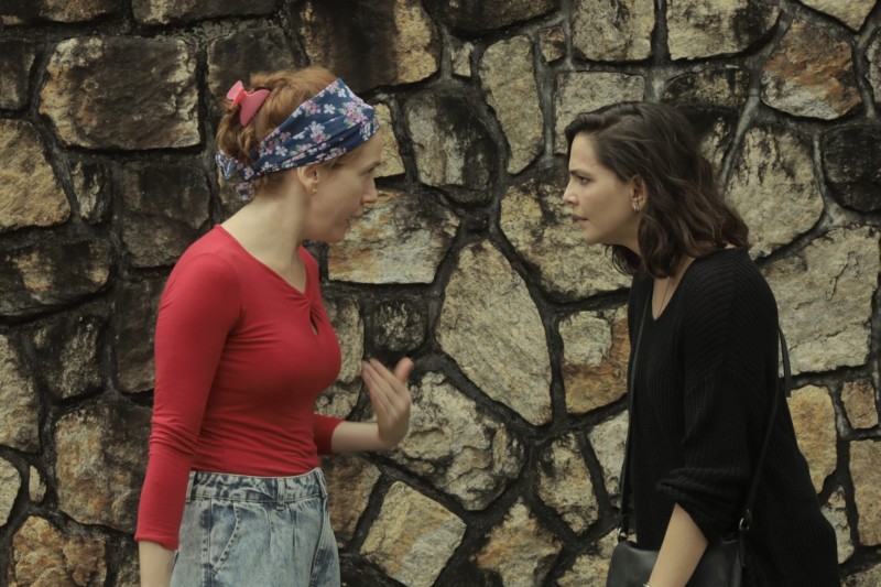 Personagens de Camila Morgado e Tainá Muller conversam em frente a um paredão de pedra