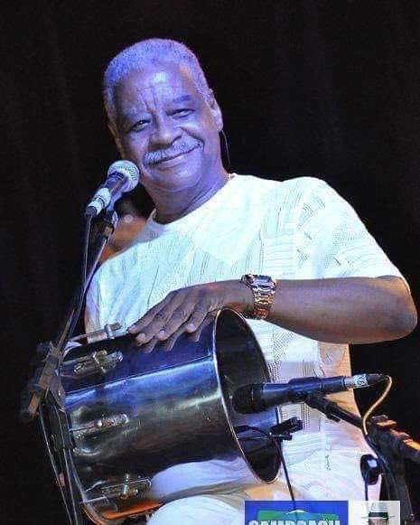 Ubirany Félix, no palco, sorri e segura o instrumento que criou