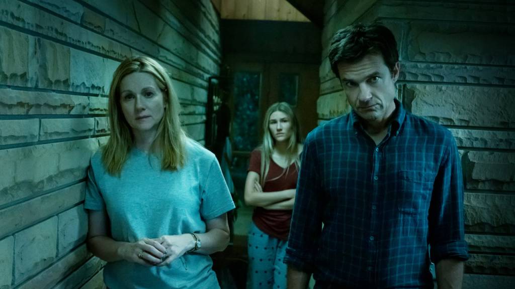 Personagens de Ozark olham para a câmera num ambiente inóspito, em tons escuros