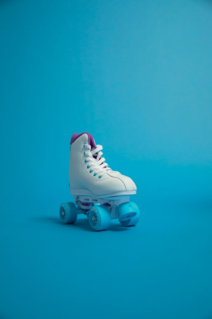 um pé de patins modelo retrô, branco de rodas azuis, num fundo azul