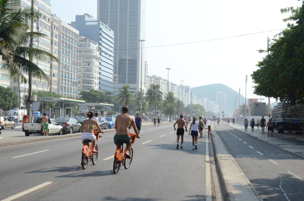 A imagem mostra a área de lazer da orla com pessoas caminhando e andando de bicicleta