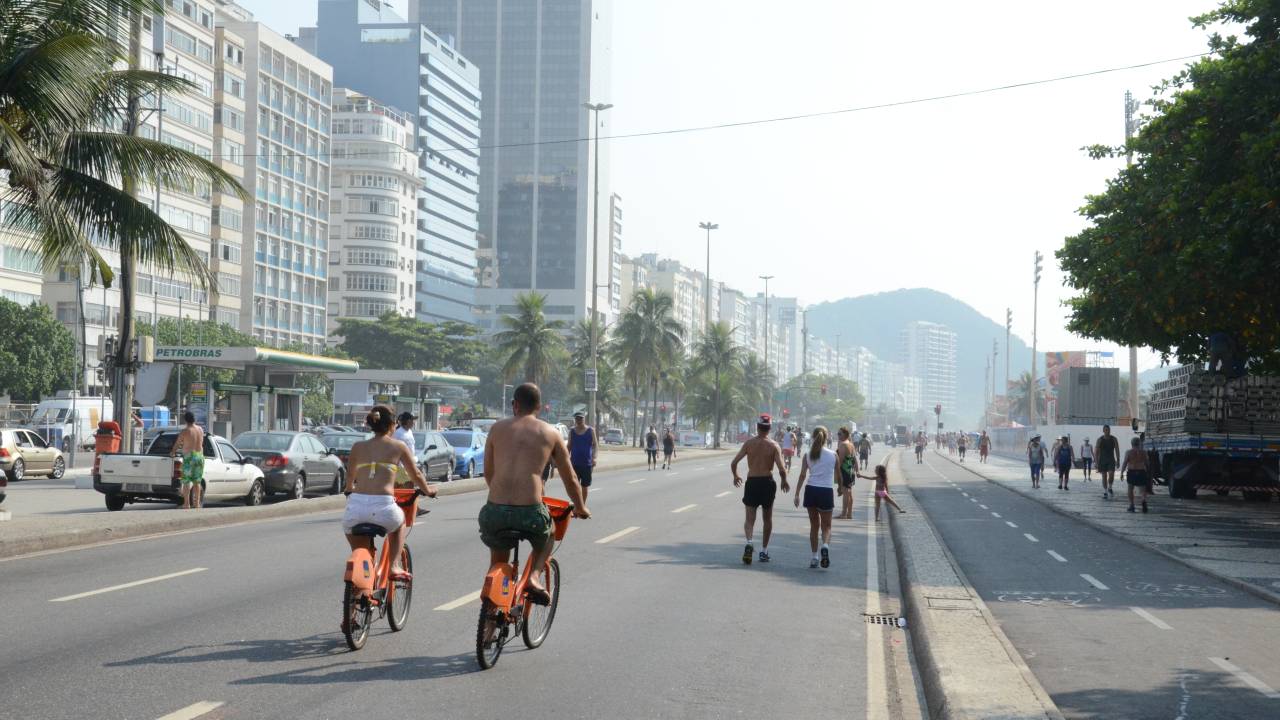 A imagem mostra a área de lazer da orla com pessoas caminhando e andando de bicicleta