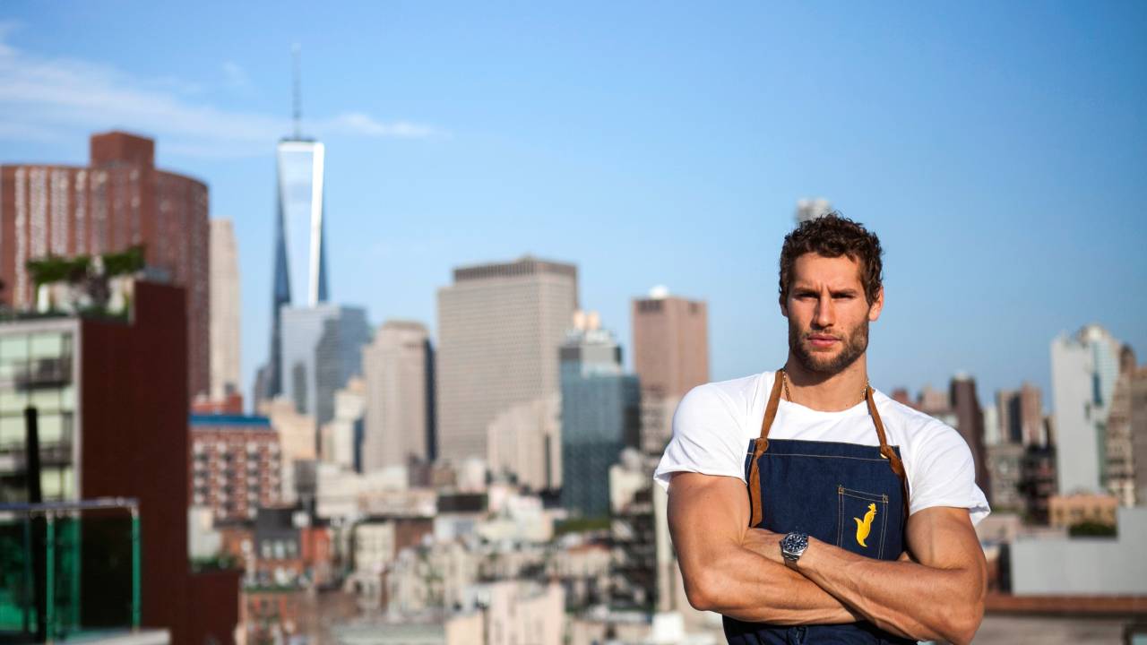 A imagem mostra o chef Franco Noriega, peruano, em frente aos prédios de Nova Iorque