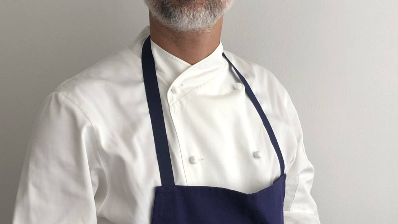 A imagem mostra um chef de cozinha vestido com roupa de trabalho