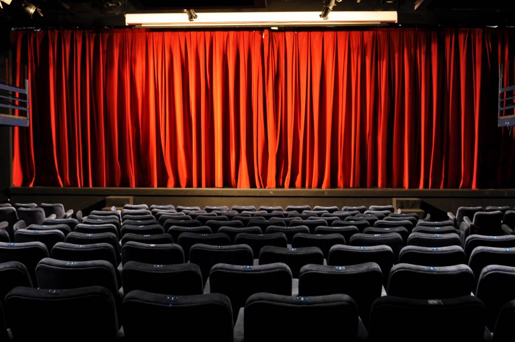 Teatro PetraGold vazio, com as cortinas vermelhas fechadas