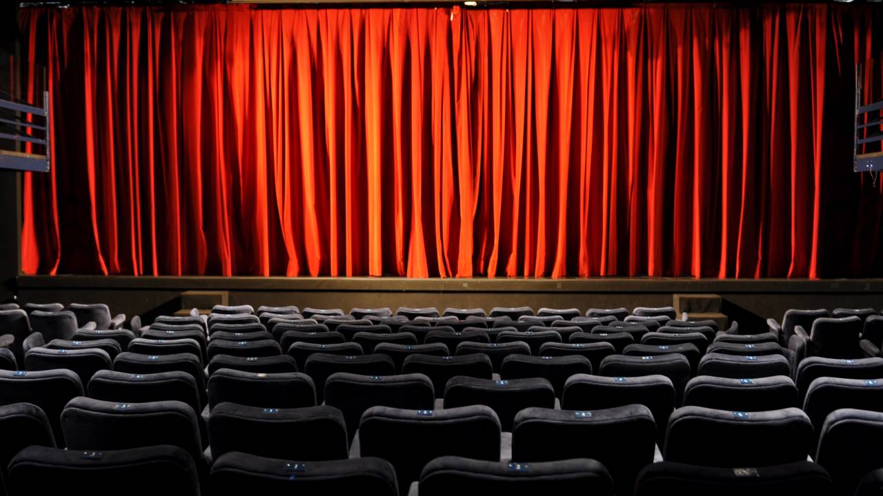 Teatro PetraGold vazio, com as cortinas vermelhas fechadas