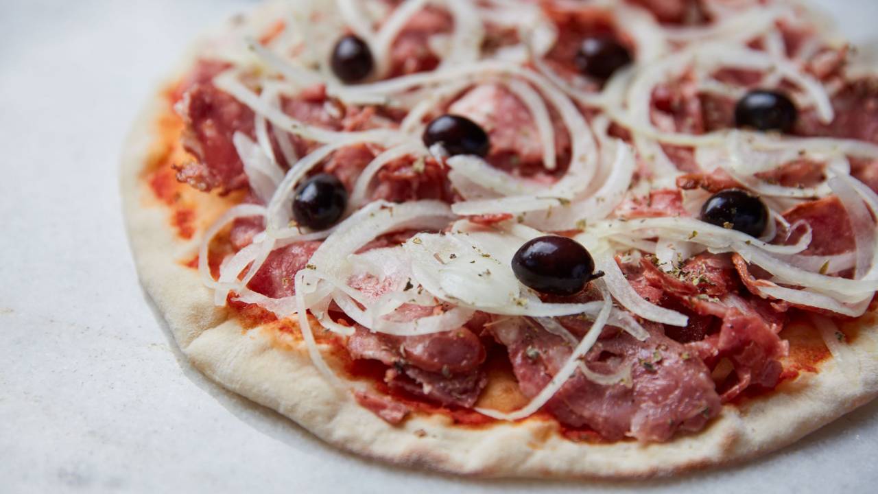 A imagem mostra um disco de pizza sabor calabresa