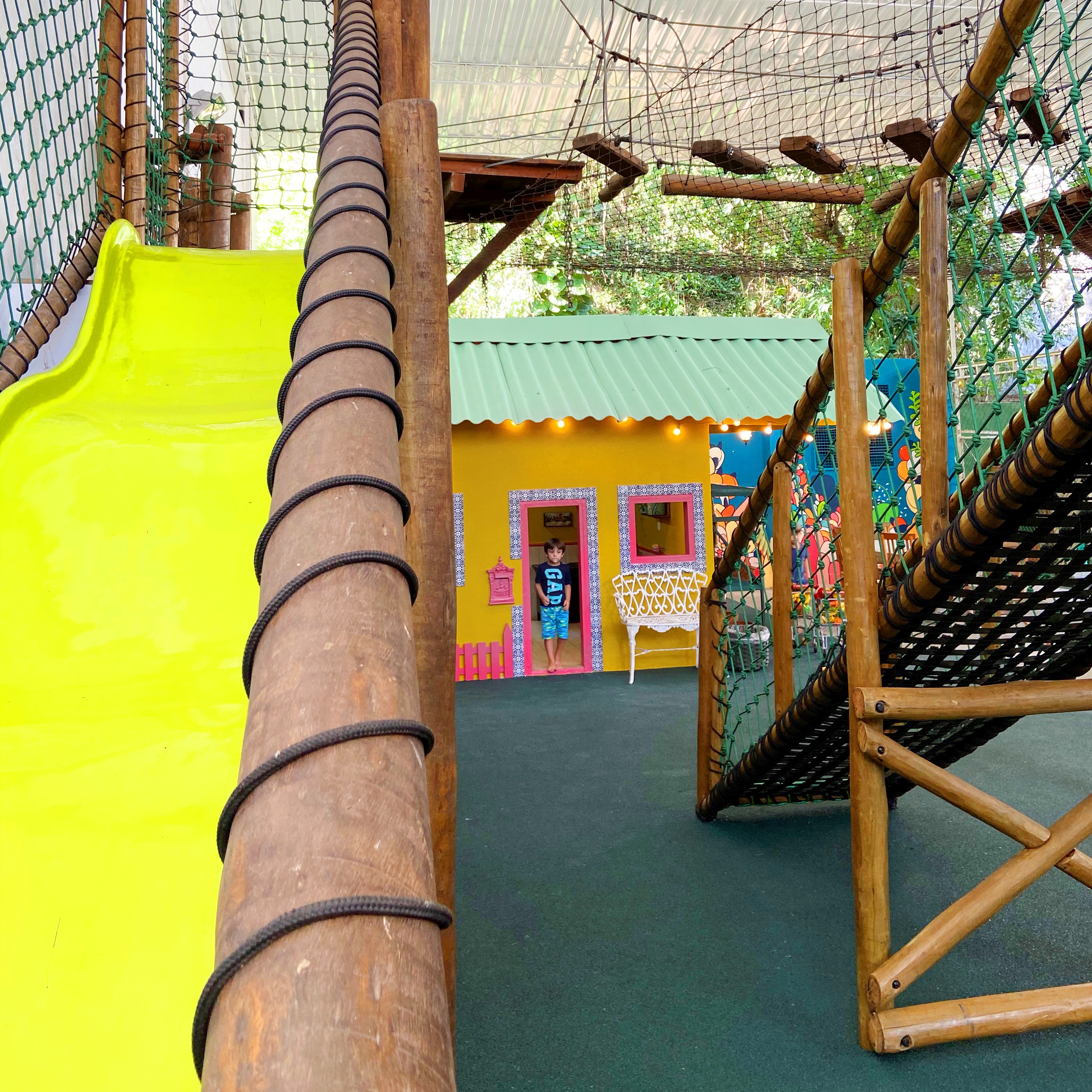 Espaço Aldeia1 Casa de festas com brinquedão e criança brincando ao fundo