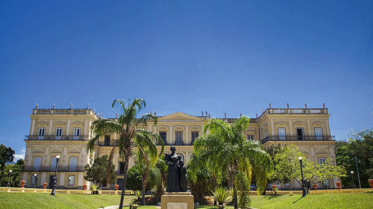 A imagem mostra a fachada do Museu Nacional em meio a um jardim