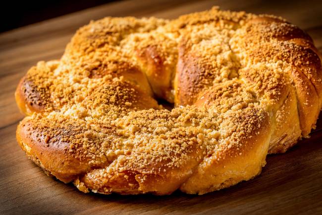 A imagem mostra uma rosca de reis, pão doce redondo coberto de frutas cristalizadas