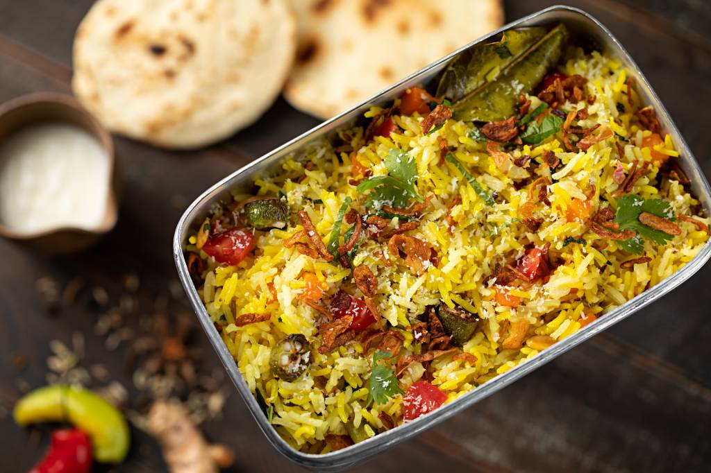 A imagem mostra um tabuleiro cheio de arroz indiano com vegetais