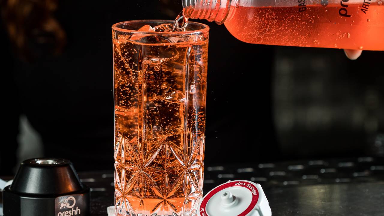 A imagem mostra um drinque em copo longo com gelo