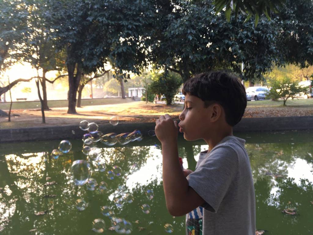 Menino sopra bolhas de sabão em frente a um lago