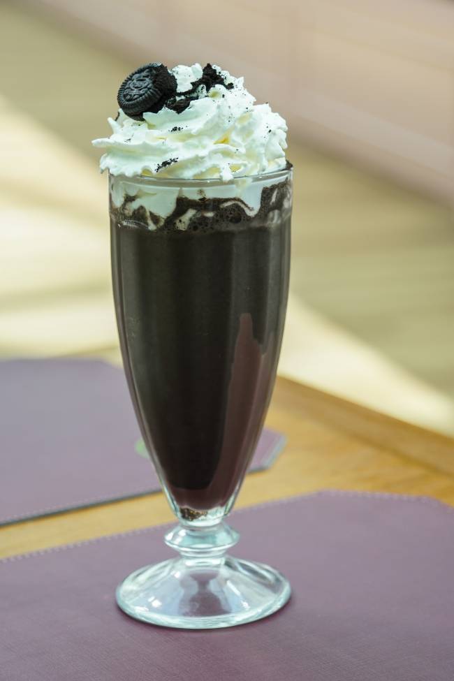 A imagem mostra um milk-shake finalizado com biscoito Oreo