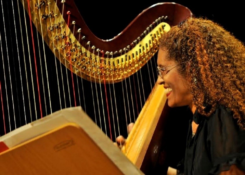 a imagem mostra uma musicista em frente a uma harpa