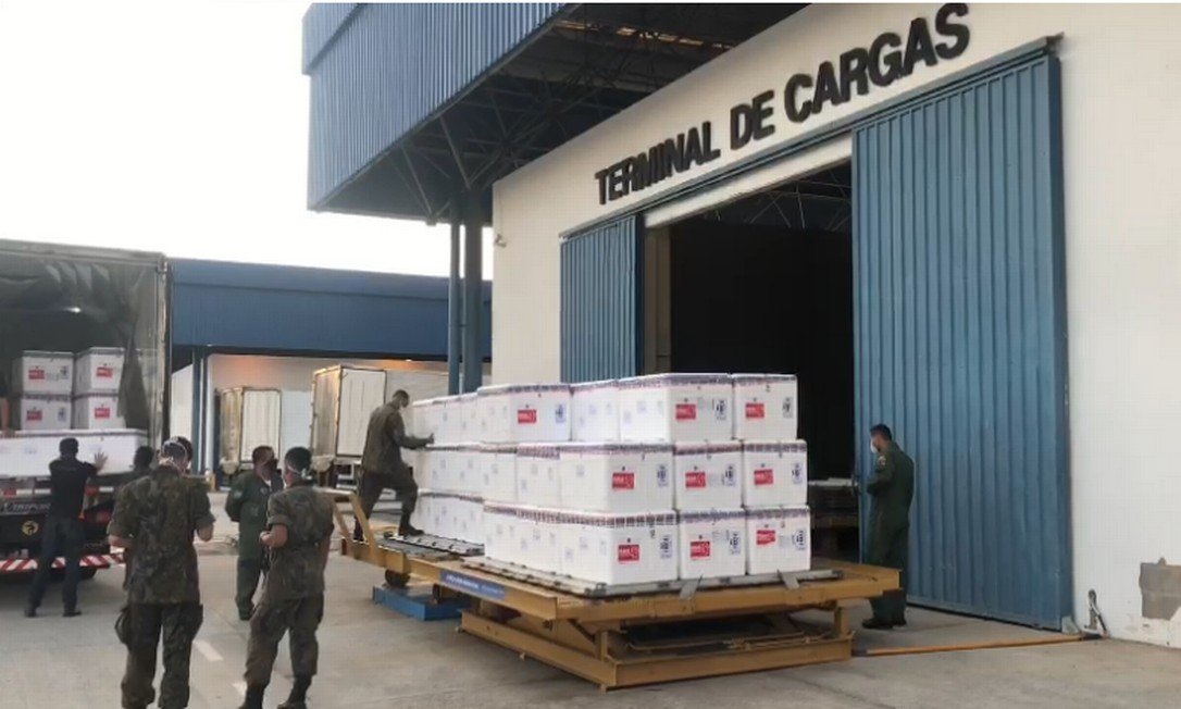 A imagem mostra um carregamento de vacinas contra a Covid-19 sendo despachado no aeroporto
