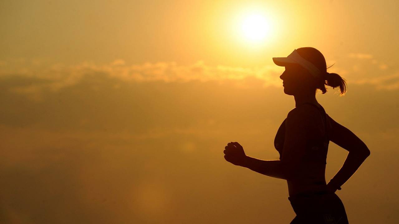Mulher pratica corrida ao nascer do sol.
