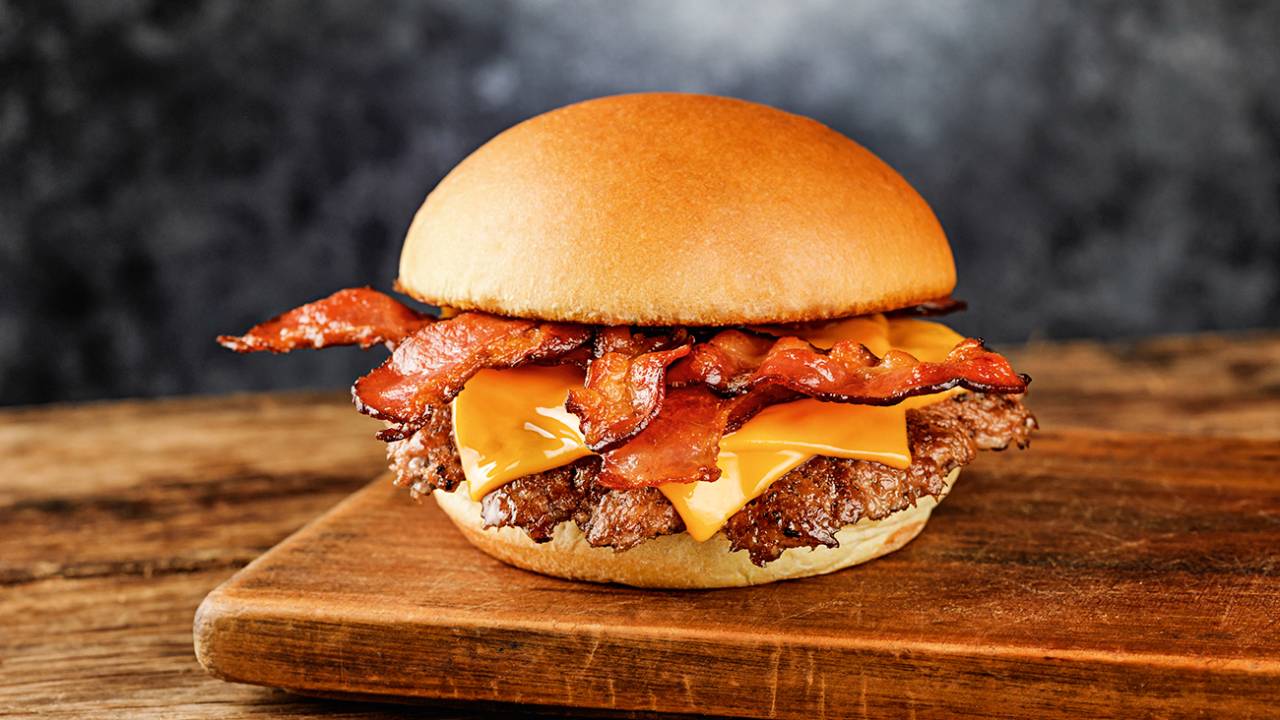 A imagem mostra um hambúrguer com queijo e bacon