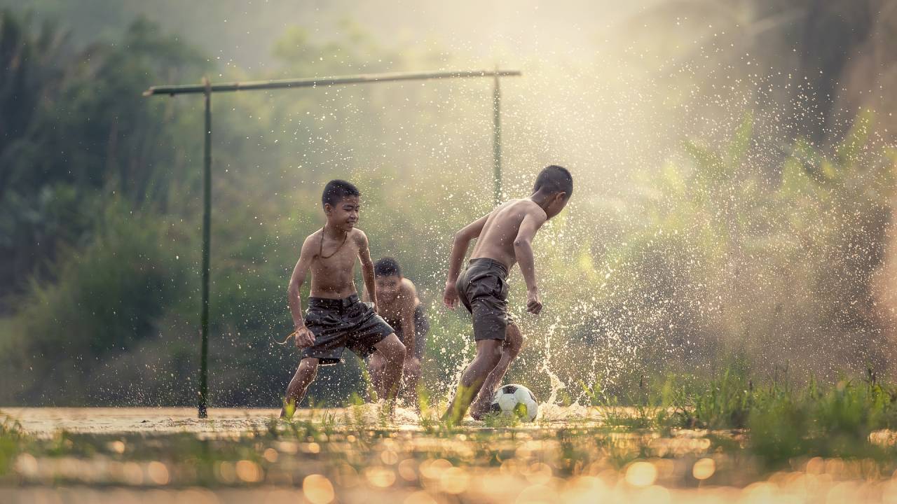 crianças jogando bola num campinho