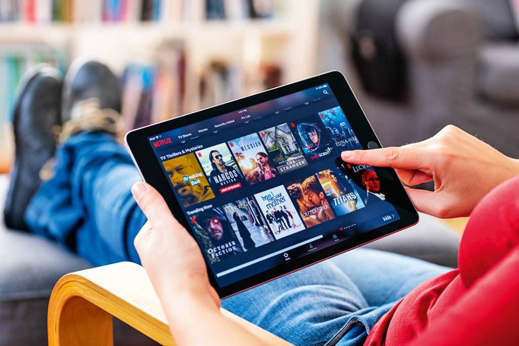 Pessoa segurando um tablet com o app da Netflix