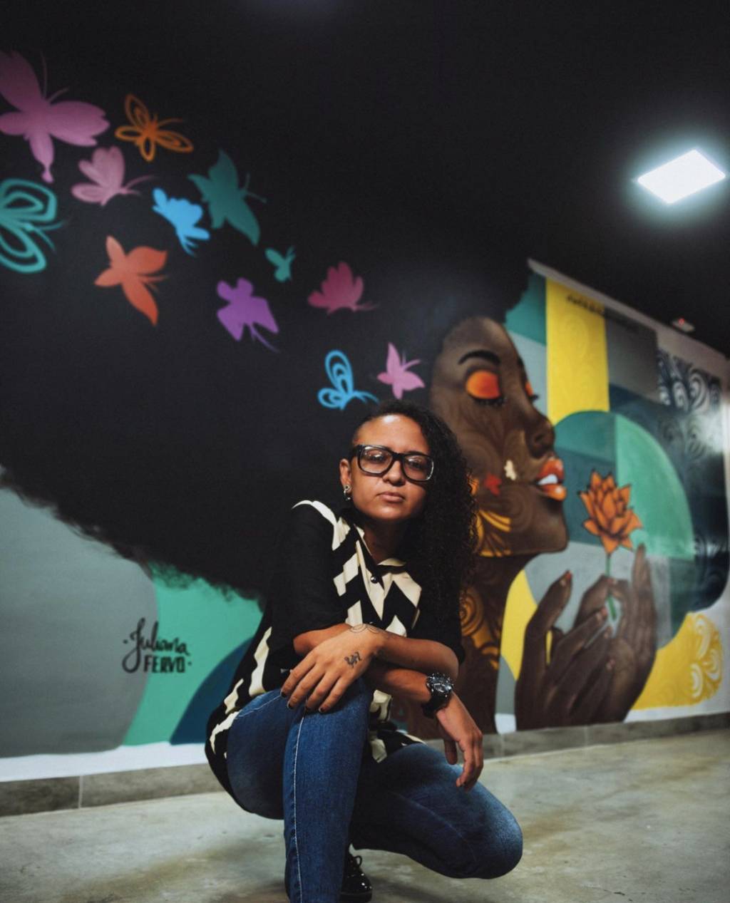 Mulher posa em frente a mural grafitado